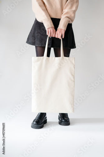 Girl holding white cotton tote bag on white background. Template can be used for you design 