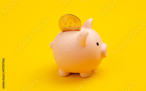 Piggy bank with bitcoin on yellow background