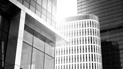 Downtown corporate business district architecture. Glass reflective office buildings against sky. Economy, finances, business activity concept. Rising sun on the horizon. Black and white.