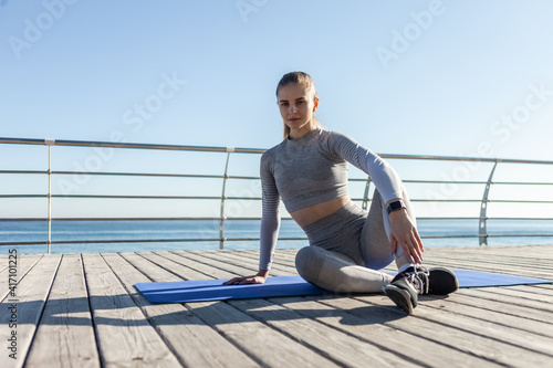 Caucasian fit woman sitting resting on a mat on the beach. Healthy lifestyle