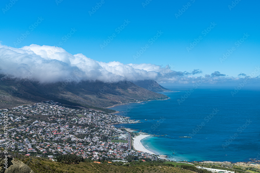Stadt am Meer mit weißem Strand im Hintergrund Wolkenband und Berge in Südafrika