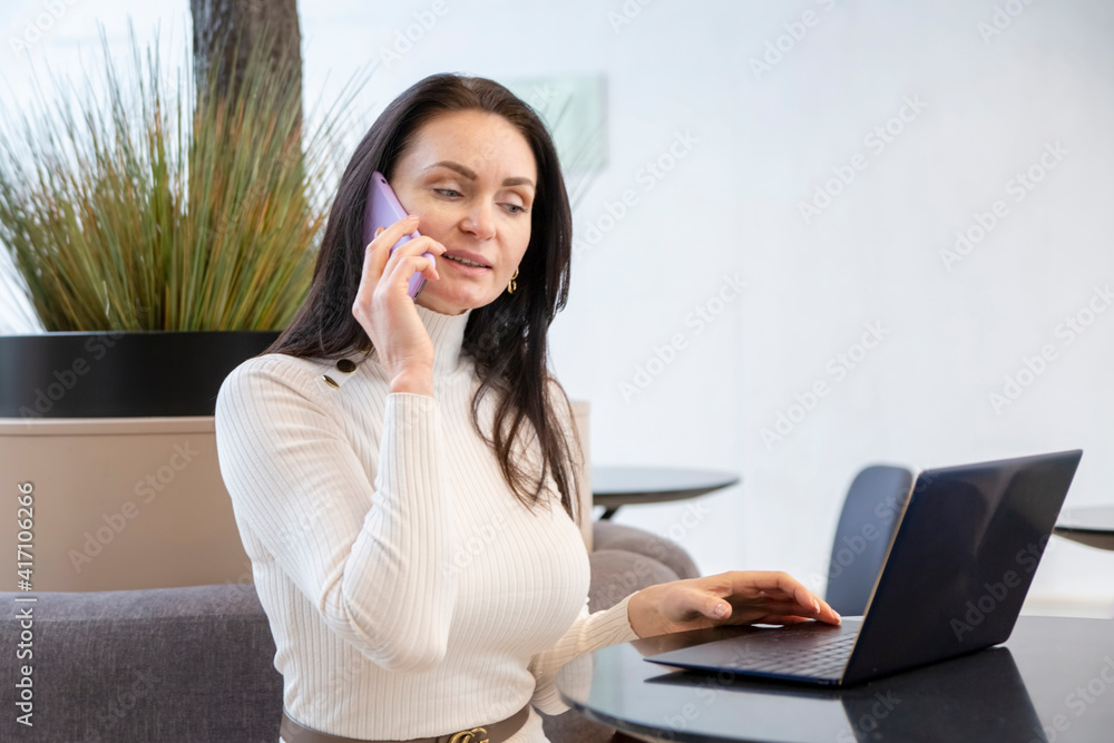 young woman works on laptop and smartphone in cafe. young woman works on laptop and smartphone in cafe.