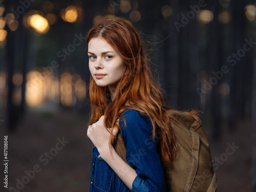 Happy woman travels among pine trees in nature in the forest