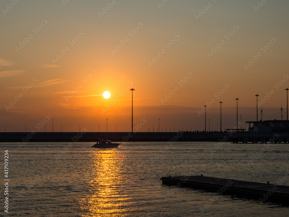 The boat crosses the path of glare into the sea under the setting sun in the sky The boat crosses the path of glare into the sea under the setting sun in the sky