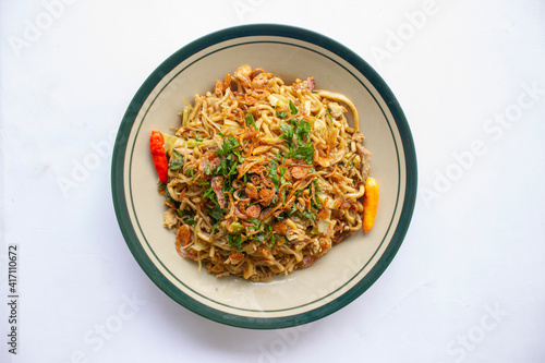 Mie Goreng Jawa or bakmi jawa or java noodle with
spoon and fork. Indonesian traditional street food noodles from central java or Yogyakarta, indonesia on white background. photo