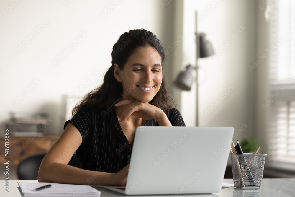 Close up smiling young woman looking at laptop screen, reading good news in message, watching video, chatting in social network or shopping online at home, enjoying leisure time with computer Close up smiling young woman looking at laptop screen, reading good news in message, watching video, chatting in social network or shopping online at home, enjoying leisure time with computer
