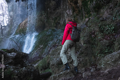 Junge Frau steht in Wanderkleidung und Rucksack im Winter vor dem Ende edes Uracher Wasserfalls auf der schwäbischen Alb  photo