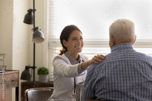 Fototapeta Naklejka Na Ścianę i Meble -  Rear view smiling female doctor wearing uniform comforting mature man, touching shoulder, good news, medical checkup results, physician therapist expressing empathy, psychological help concept