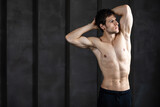 Portrait of athletic man without a shirt against dark background.