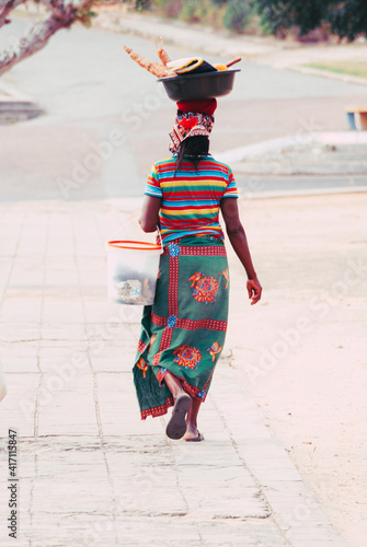 Inhambane, Mozambique, September 13th 2018: African woman with typical clothes carrying packages and big bags