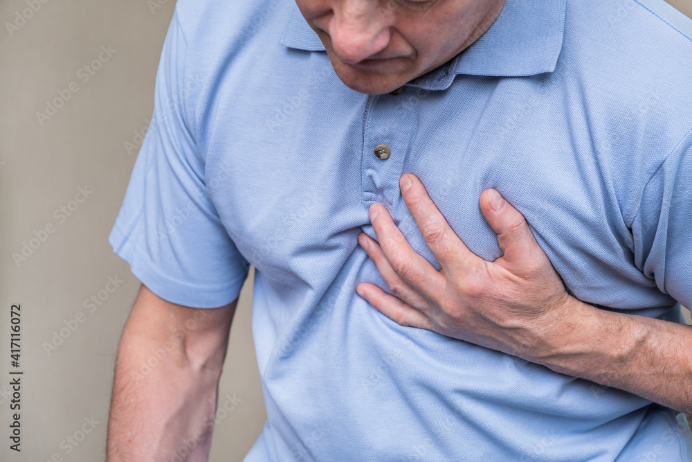 Heart pain, a person grabbing the heart area with his hand, suffering