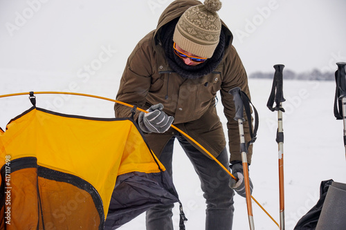 Two guys are setting up a tent in the snow. Setting up a tent during a winter expedition in extreme conditions. Winter trekking © Serhii Prystupa