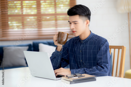 Young business man working from home with laptop computer on desk, freelance male sitting stay home using notebook for communication and relax on table, entrepreneur in startup business, new normal.