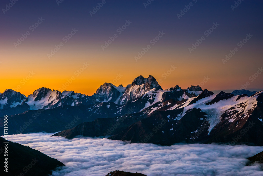 Snowy Greater Caucasus ridge with the Mt. Ushba at vibrant summer sunrise. View from 