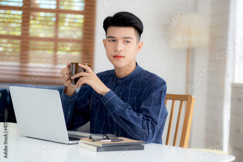 Young business man working from home with laptop computer on desk, freelance male sitting stay home using notebook for communication and relax on table, entrepreneur in startup business, new normal.