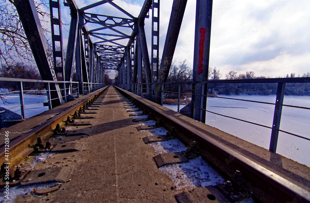 an abandoned railway bridge over a frozen river