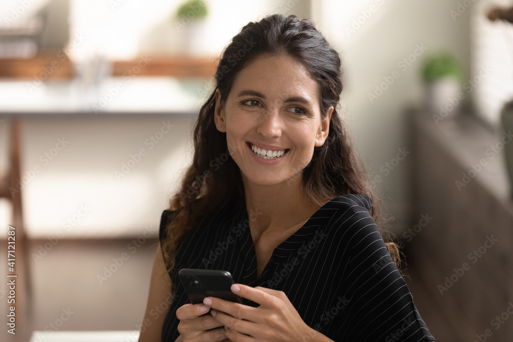 Close up smiling dreamy woman distracted from phone, happy young female dreaming about new opportunities, visualizing, waiting for call, sitting on couch, holding smartphone, looking to aside Close up smiling dreamy woman distracted from phone, happy young female dreaming about new opportunities, visualizing, waiting for call, sitting on couch, holding smartphone, looking to aside