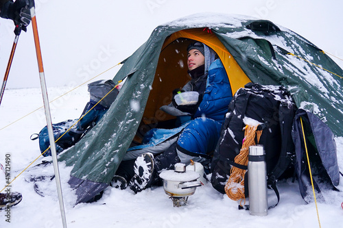 The guy in the tent eats porridge from a plate during winter travel