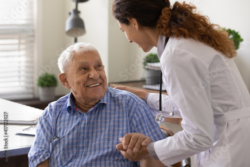 Fotografie Close up caring nurse holding smiling mature patient hand at meeting in hospital
