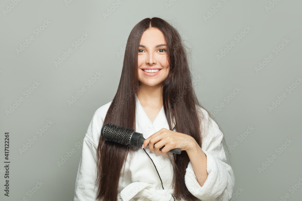 Beautiful woman combing her long brown hair on white background. Haircare concept Beautiful woman combing her long brown hair on white background. Haircare concept