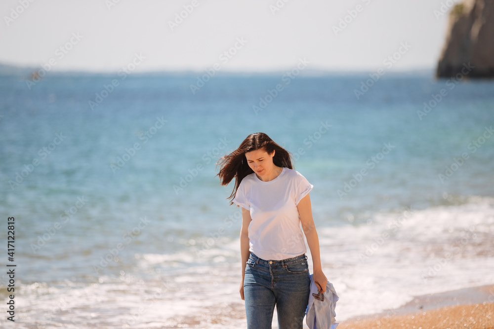 Young woman in jeans is walking along the beach. Sea in england. vacations at the beach 