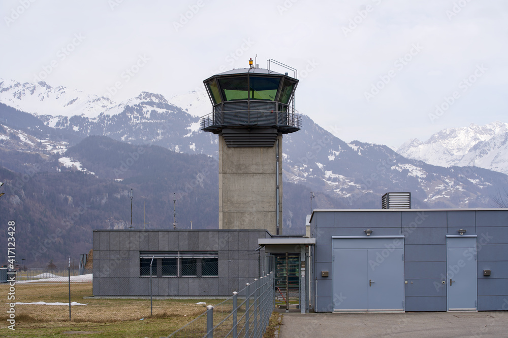 Obraz premium Flight control tower of military airbase with snow mountain panorama in the background. Photo taken February 26th, 2021, Meiringen, Switzerland.