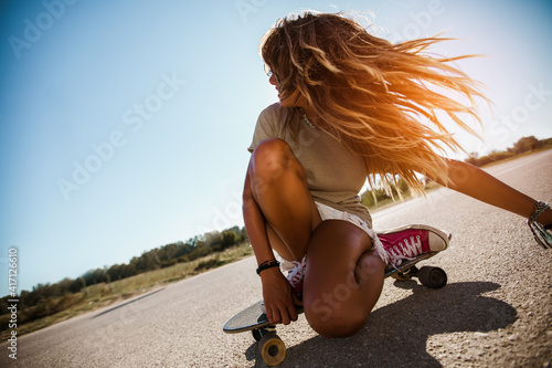 Sporty woman riding on the skateboard on the road. Longboarding, female.