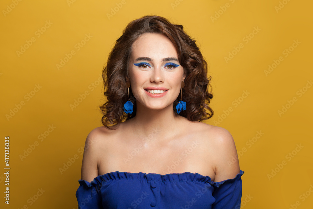 Happy woman fashion model in blue top on yellow background Happy woman fashion model in blue top on yellow background