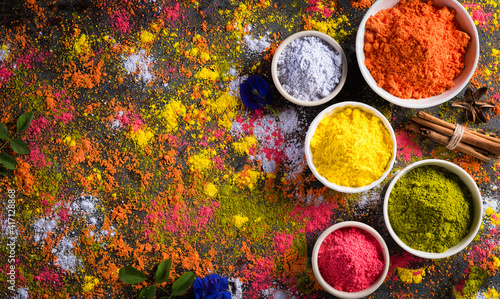 Holi festival celebration. Traditional Indian Holi colours powder decoration with paints. Top view of Organic Gulal colors in bowls ondark background. photo