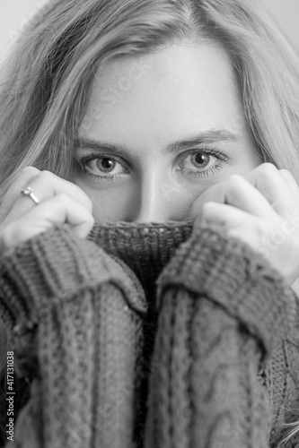 portrait of a woman in a knitted sweater, black and white shot, mouth covered with hands, sharpness on the eyes,