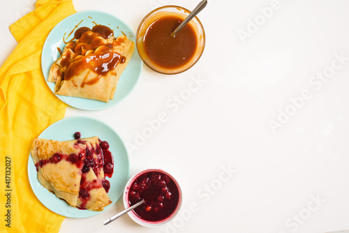 blini pancakes with red berry jam close-up on a blue plate on a light background . traditional Russian holiday is a symbol of spring and sweet dessert