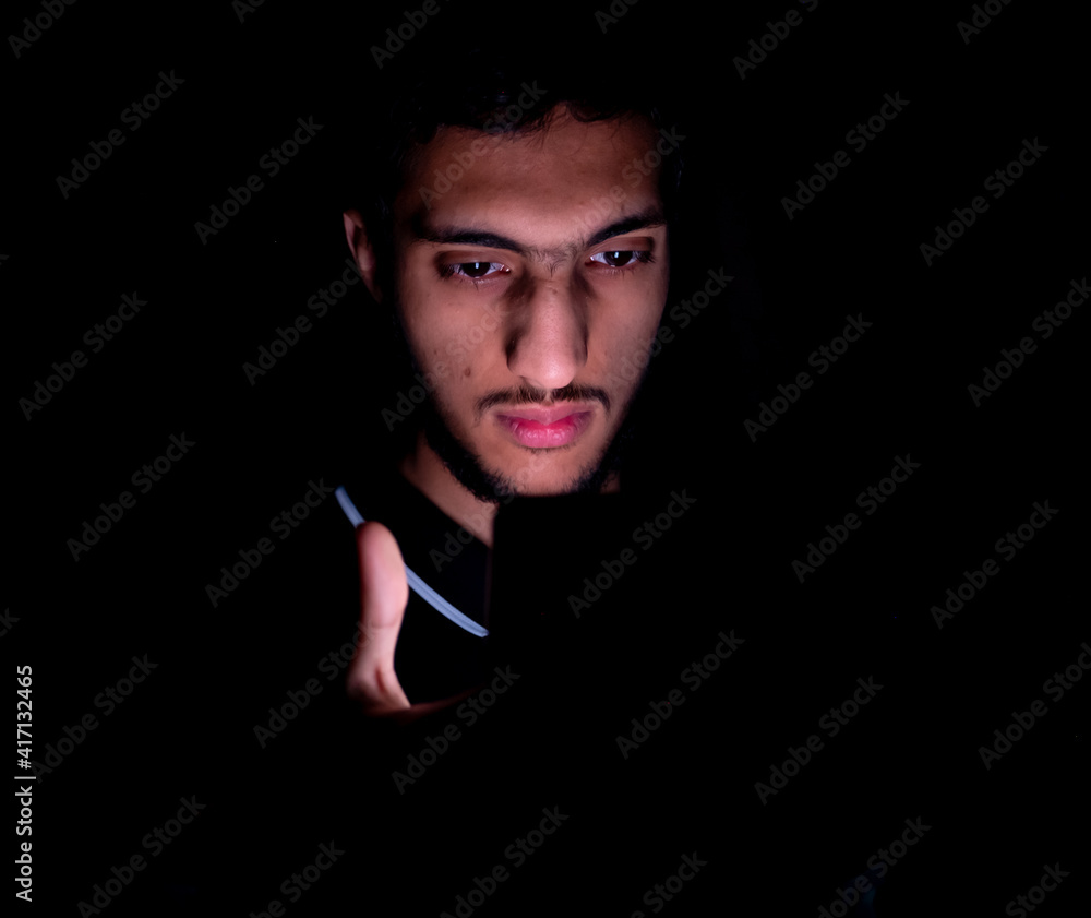 Portrait of middle eastern guy checking his phone in a dark room Portrait of middle eastern guy checking his phone in a dark room