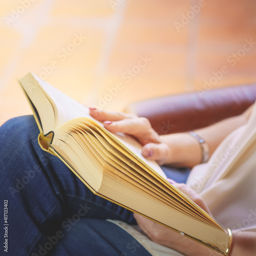 White woman reading a book in an armchair relaxing in nice daylight outside. Copy space. Reading, teaching concept.