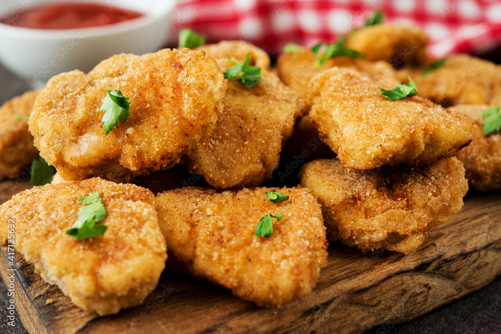 Homemade chicken nuggets with herbs and ketchup on a wooden board Homemade chicken nuggets with herbs and ketchup on a wooden board
