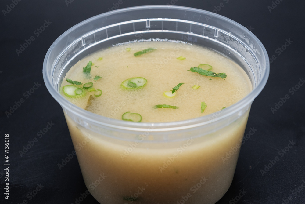 Bowl of Miso soup shows delicious cloudy broth containing green onion, seaweed, and spicy flavor in clear container. Bowl of Miso soup shows delicious cloudy broth containing green onion, seaweed, and spicy flavor in clear container.