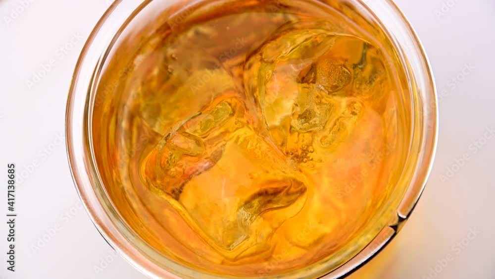 Top view of whiskey glass with ice cubes spinning Top view of whiskey glass with ice cubes spinning