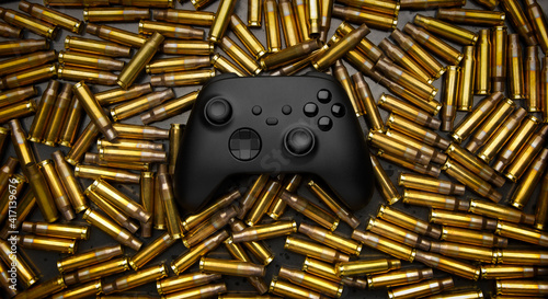 Cuadro en lienzo Modern black gamepad on a black background among the spent cartridges