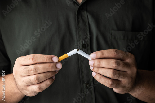 The young man used his hand to break a cigarette into two. He wants to quit smoking for good health. world tobacco day.