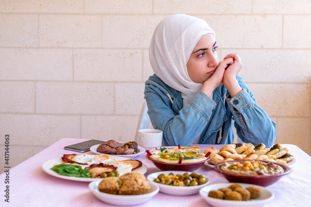 Muslim girl is thinking while eating her breakfast Muslim girl is thinking while eating her breakfast