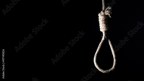 Rope noose with hangman knot in front of dark background. suicide loop photo