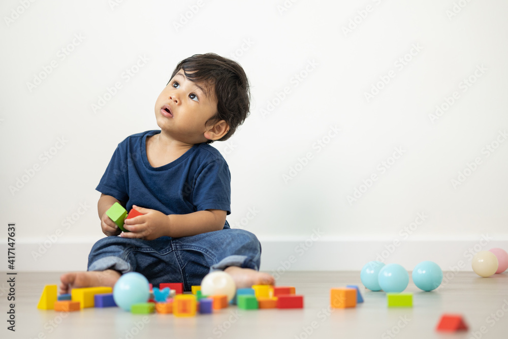 An Asian boy about 1 year old. Playing in the living room in the house He plays wooden toys in different colors. He is wearing a blue shirt. An Asian boy about 1 year old. Playing in the living room in the house He plays wooden toys in different colors. He is wearing a blue shirt.