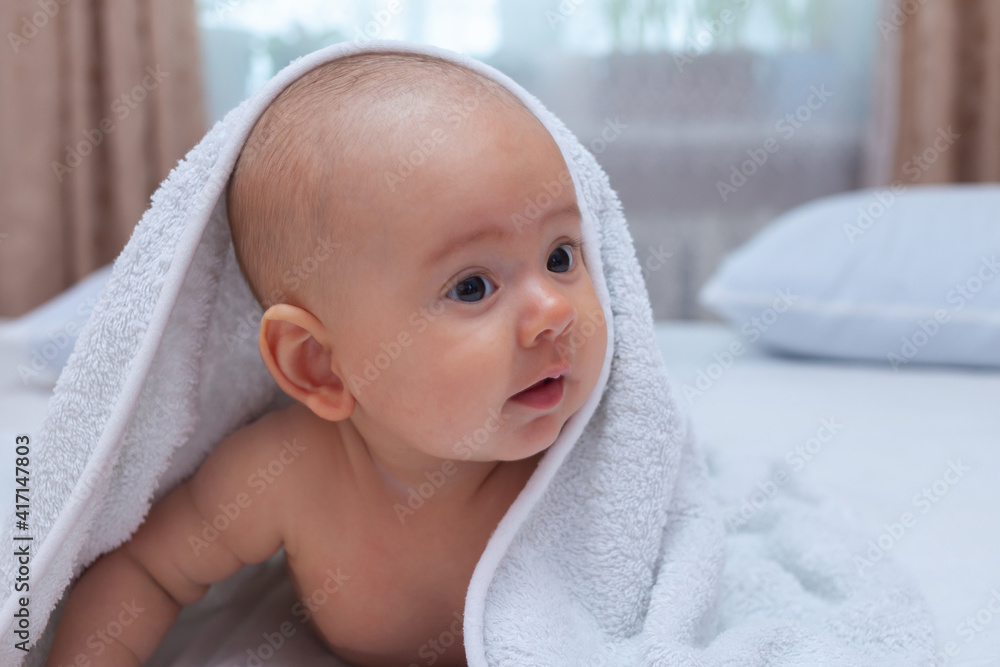 Funny baby in a white towel after bathing. Home interior Funny baby in a white towel after bathing. Home interior