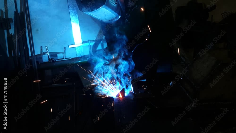 A working welder welds a construction or structures made of metal and iron. Construction and repair work.The welder welds metal structures. The builder at work. Semi-automatic welding machine at work A working welder welds a construction or structures made of metal and iron. Construction and repair work.The welder welds metal structures. The builder at work. Semi-automatic welding machine at work