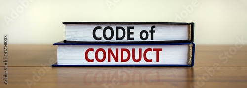 Code of conduct symbol. Concept words 'Code of conduct' on books on a beautiful wooden table, white background. Business and code of conduct concept. Copy space.