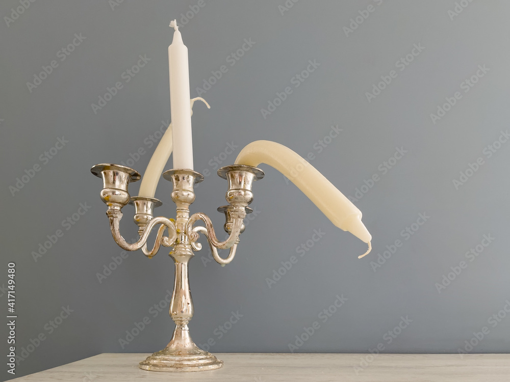 Candlestick with straight and bent candles. Metaphor of erectile dysfunction impotence. Creative concept of male potency problems. Sexual dysfunction in men, problems with health. - obrazy, fototapety, plakaty 