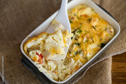 baked cauliflower with chicken fillet and vegetables topped with cheese