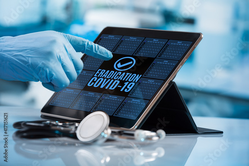 Doctor touching the screen of an electronic diary with the message covid-19 eradication. Doctor working with tablet in calendar of the pandemic vaccine plan for eradication of Coronavirus