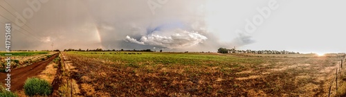 Panoramic image of a storm with rainbow and sunset.