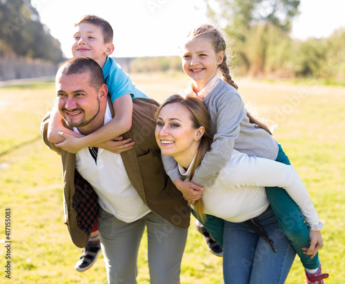 happy family of parents with two children enjoy a walk in city park