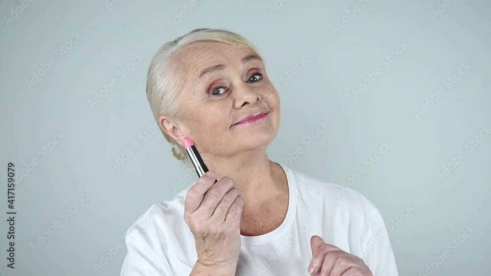Smiling senior woman holding lipstick in hand Smiling senior woman holding lipstick in hand